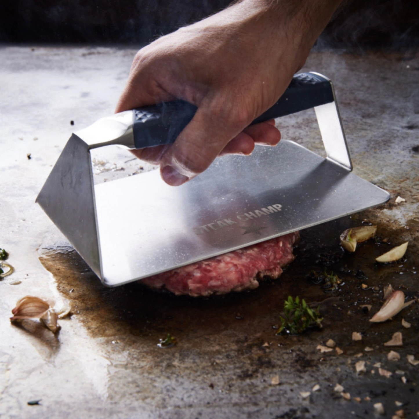 Steak Champ pers in gebruik op een hete barbecue